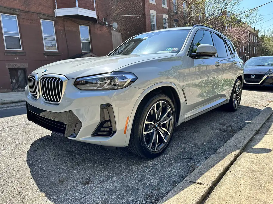 Gray BMW X3 at the curb of a red-brick rowhouse street