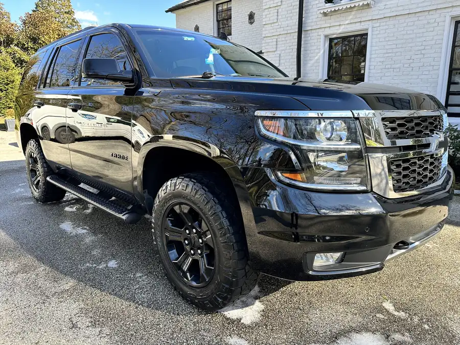 Black Chevy Tahoe after a detail, wet-polish reflections running down the doors
