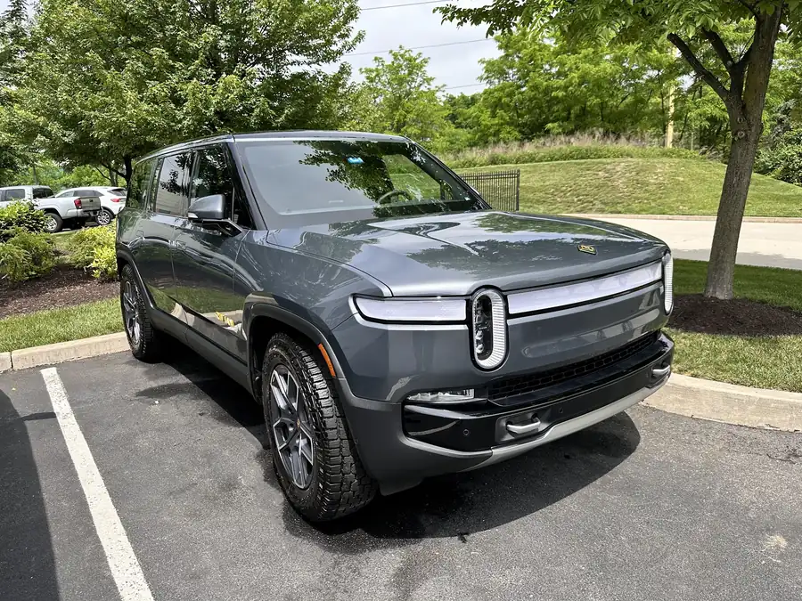 Gray Rivian R1S in a parking bay after a detail, trees behind